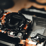 A disassembled DSLR camera body on a repair bench with precision screwdrivers.